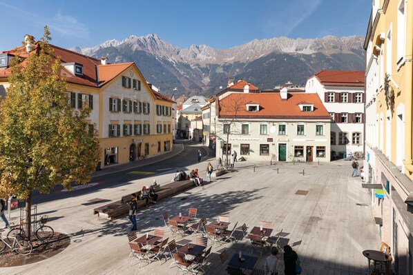 A square with outdoor seating, buildings with traditional architecture, and a mountain backdrop.