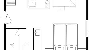 Ein Grundriss eines Hotelzimmers mit Bett, Schreibtisch, Stuhl, Kleiderschrank und Badezimmer.