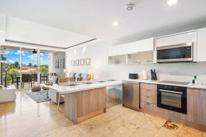 A modern kitchen with a central island, built-in appliances, and a view to an outdoor area.