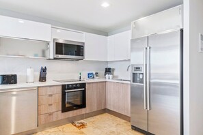 A modern kitchen with stainless steel appliances, a microwave, and a refrigerator.