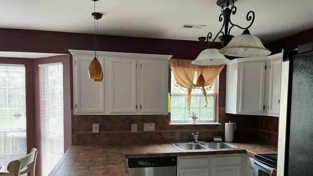A kitchen with white cabinets, a dishwasher, a sink, and a stove. - Cozy home minutes from PNC and Nascar Speedway (Charlotte)