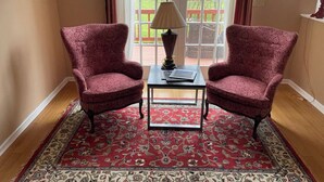 A room with two red upholstered chairs, a small table with a lamp, and a patterned rug. - Cozy home minutes from PNC and Nascar Speedway (Charlotte)