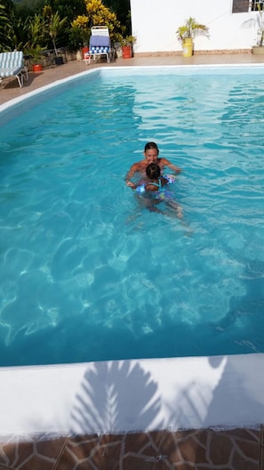 A swimming pool with clear blue water, surrounded by lounge chairs and potted plants. - Holiday House Second floor Ste (Montego Bay)