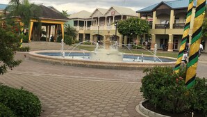 A courtyard with a central fountain, surrounded by buildings with balconies and a covered area. - Holiday House Second floor Ste (Montego Bay)