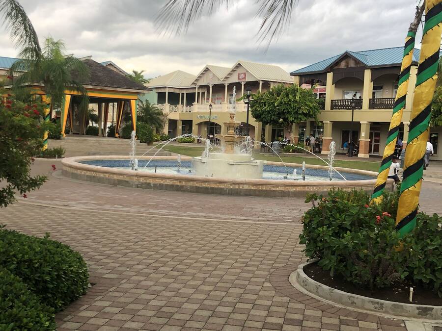 A courtyard with a central fountain, surrounded by buildings with balconies and a covered area.