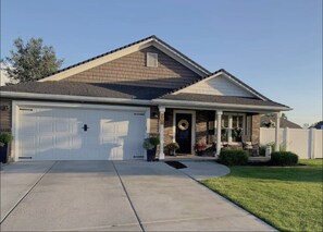 Stylish home with a gabled roof and brick facade, featuring a front porch and well-maintained lawn.