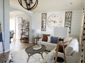 Cozy living space with a large wall clock, comfortable sofa, and decorative panels.