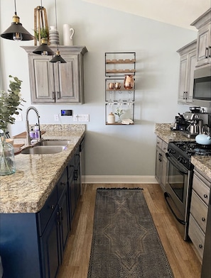 Compact kitchen with an oven, stainless steel sink, and range hood.