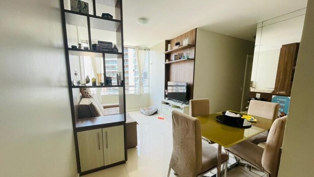 A modern living room with a dining area, a bookshelf, and a television.