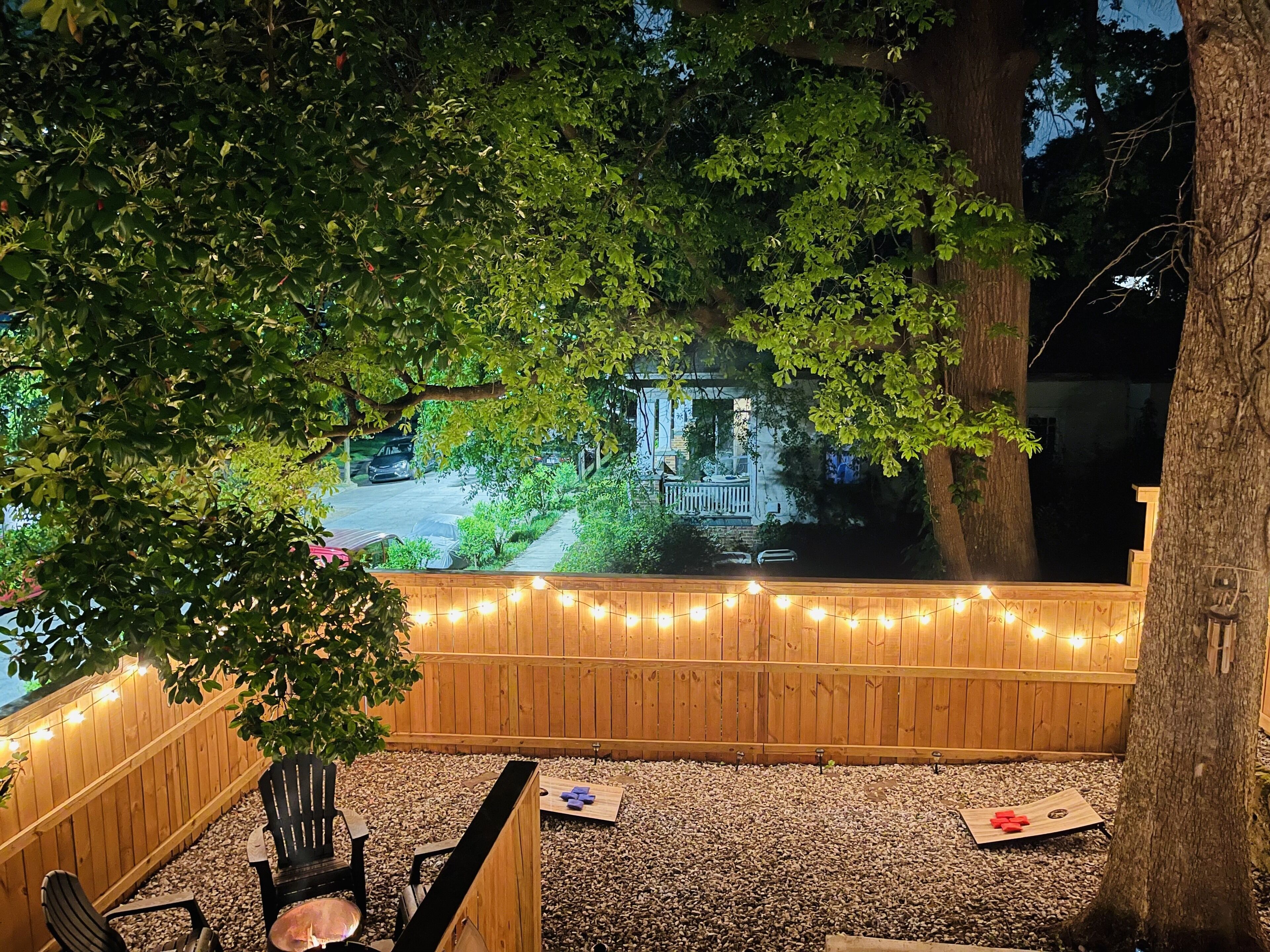 Un espace patio avec une terrasse en bois, des guirlandes lumineuses et des sièges d’extérieur.