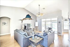 Relax in this stylish living room with a high ceiling, large windows, and a comfortable L-shaped sofa set.