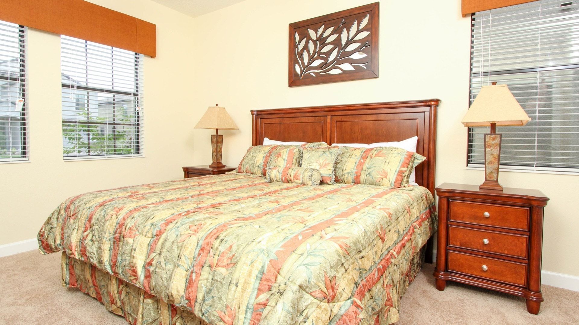 A bedroom with a large bed, two bedside tables, a nightstand, and a window with blinds.