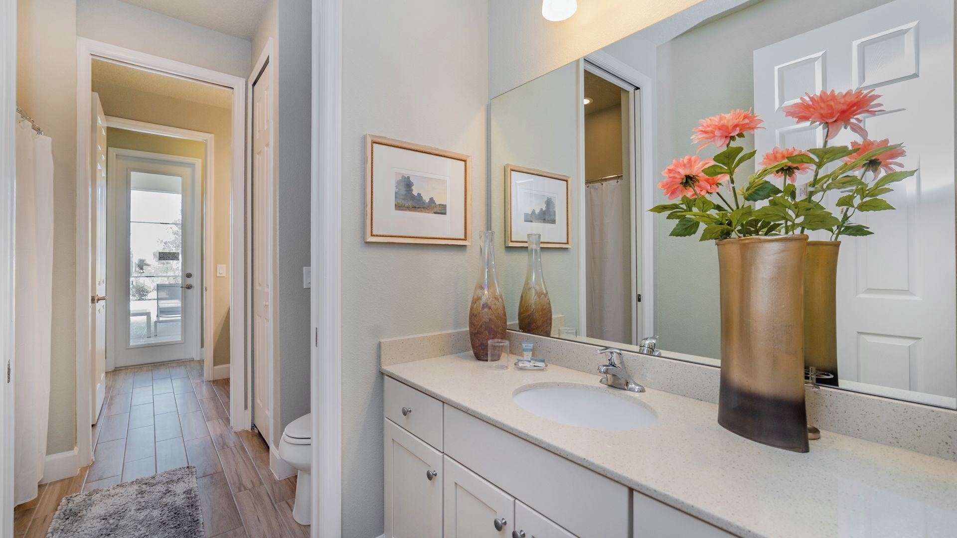A bathroom with a sink, mirror, and two framed pictures on the wall.