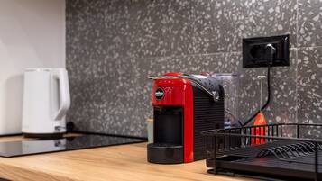A kitchen with a coffee machine, a kettle, and a power outlet on the wall.