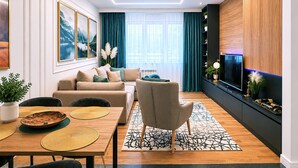 Een moderne woonkamer met een bank, eettafel en televisie.