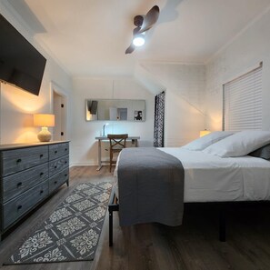 Un dormitorio con cama, cómoda, escritorio y ventilador de techo.