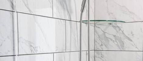 Une douche équipée d’un pommeau de douche à main et de commandes murales.