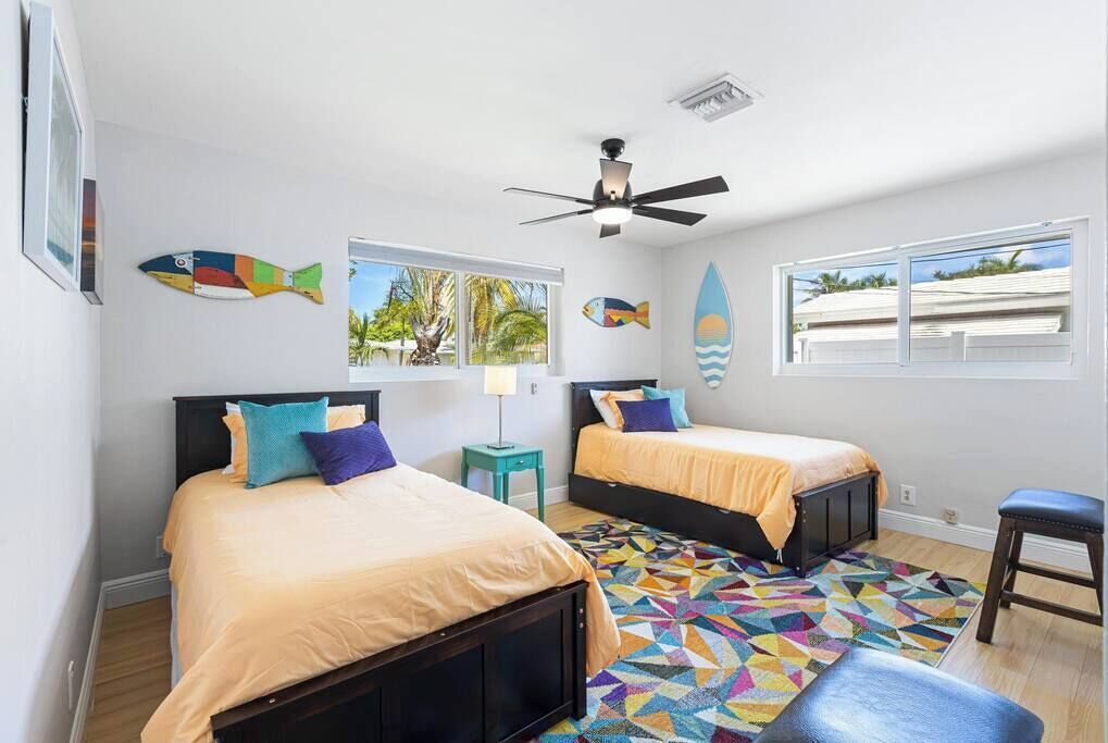 A bedroom with two beds, a ceiling fan, and a colorful geometric rug.