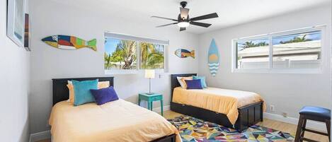 A bedroom with two beds, a ceiling fan, and a colorful geometric rug.