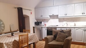 Ein Essbereich mit Tisch und Stühlen, einer Couch und einer Küche mit weißen Schränken.