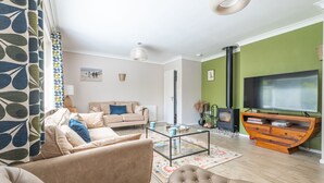 Una sala de estar con sofá, mesa de centro de vidrio, televisor y chimenea.