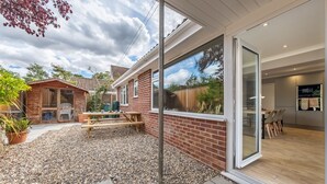 Una casa moderna con un patio, zona de barbacoa y espacio para comer.
