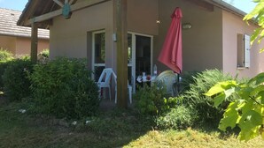 Una casa con portico coperto, una porta che dà su un ambiente interno e un piccolo tavolo con sedie.