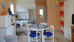 Una cucina compatta con lavatrice, un tavolo da pranzo con cuscini blu e un orologio appeso al muro.