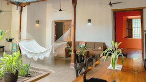 A spacious room with a wooden dining table, several chairs, a hammock, and potted plants. - Miskitu Casa Boutique (Granada)