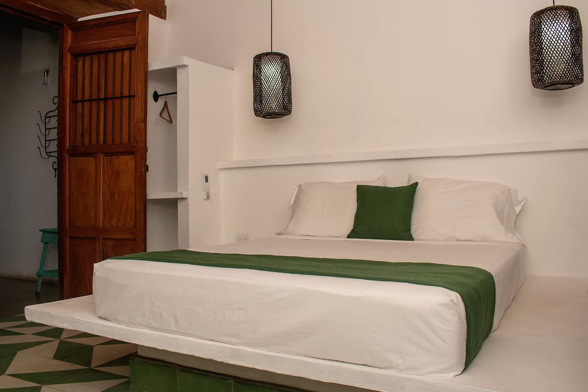 A bedroom with a bed, a wooden door, and two hanging lamps.