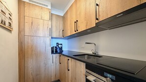 Eine moderne Küche mit Holzschränken, einer schwarzen Arbeitsplatte, einer Edelstahlspüle und einem Einbauofen.