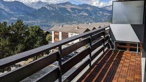 Ein Balkon mit Blick auf Berge und eine darunterliegende Stadt.