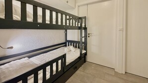 Dormitorio con literas, una puerta blanca y una pared blanca.