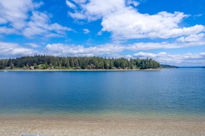 A calm lake with a forested island in the distance.