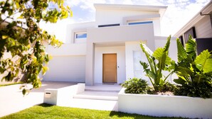 A modern two-story house with a front door, a mailbox, and a well-maintained lawn.