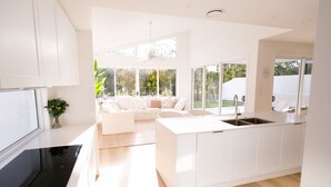 A modern kitchen with white cabinetry, a central island with a sink, and a large window offering a view of the outdoors.