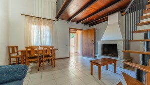 Una sala de estar con chimenea, muebles de madera y piso de baldosas.