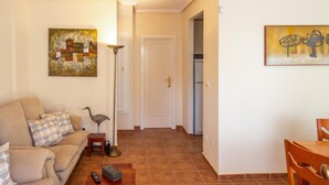 Una sala de estar con un sofá, una mesa de centro, una lámpara de pie y obras de arte en las paredes.
