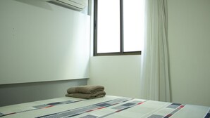 Ein Hotelzimmer mit Bett, einem Vorhangfenster und einer Klimaanlage an der Wand.