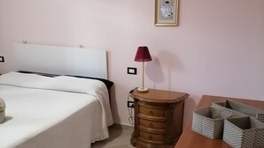 A bedroom with a bed, bedside table, lamp, dresser, and a desk with storage baskets.