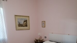 A bedroom with a bed, a nightstand, a lamp, and a framed picture on the wall.
