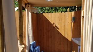 Une terrasse en bois équipée de toilettes et d’un lavabo, d’un porte-serviettes avec des serviettes, et d’un ventilateur de plafond.