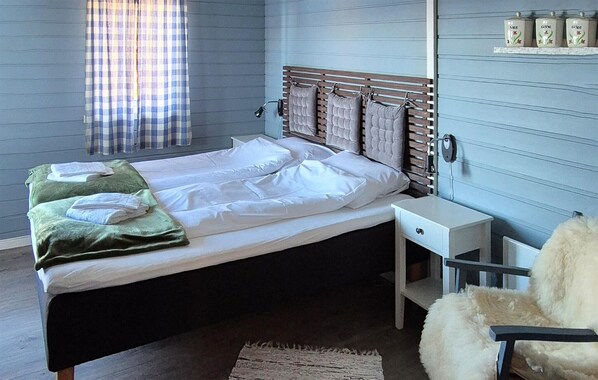 A bedroom with a bed, a bedside table, a chair, and a wall-mounted shelf with decorative items. - Awesome home in Laukvik with kitchen (Laukvik)