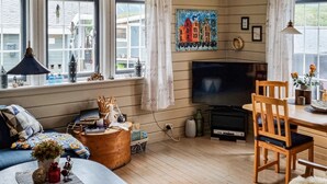 A cozy living room with a fireplace, a television, and a dining area with wooden furniture. - Awesome home in Laukvik with kitchen (Laukvik)