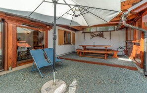 Eine Terrasse mit Tisch und Stühlen, ein überdachter Bereich mit Sonnenschirm und ein rustikales Holzinnere.