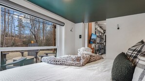 Makuuhuoneessa on suuri sänky, näkymä ulos, televisio ja ikkuna, jossa on sälekaihtimet.