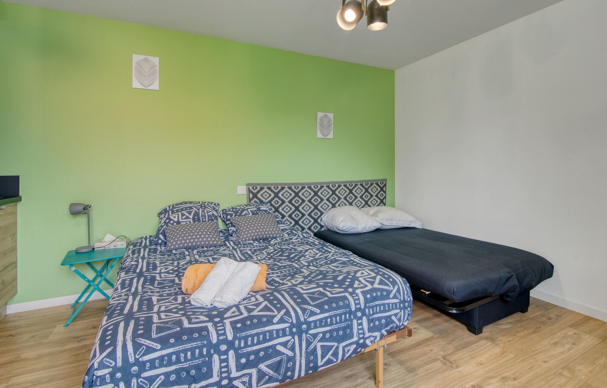 A room with a bed, a small desk, and a green wall.