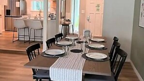 Una zona de menjador amb una taula rectangular coberta per a sis persones, envoltada de cadires negres. Hi ha un corredor de taula rayat a la taula.