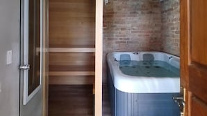 Une salle de bain avec un plancher en bois, un mur en briques et une baignoire blanche.