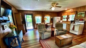 A spacious living area with a dining table, two armchairs, a sofa, and a kitchen with a stove and refrigerator.